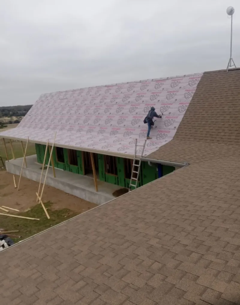 Worker preparing underlayment for a metal roof installation in Edgartown